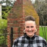Erin Tinnon, MSW, LCSW standing in front of a brick pillar wearing a black and grey plaid flannel shirt. They are wearing white spiral earrings and smiling at the camera. Erin Tinnon, MSW, LCSW standing in front of a brick pillar wearing a black and grey plaid flannel shirt. They are wearing white spiral earrings and smiling at the camera.